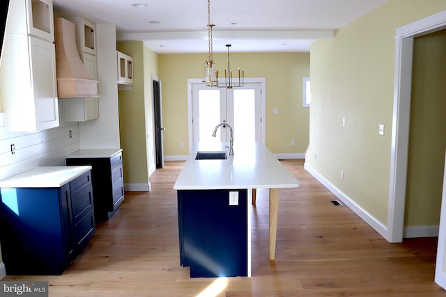 kitchen featuring pendant lighting, sink, blue cabinetry, white cabinets, and a kitchen bar