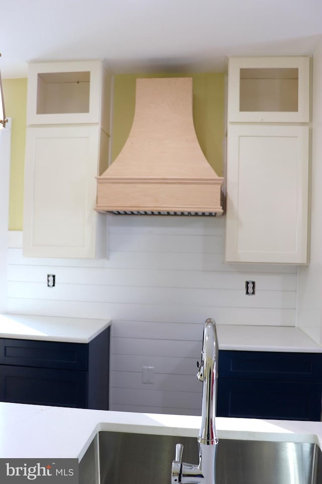 kitchen featuring white cabinetry and custom range hood