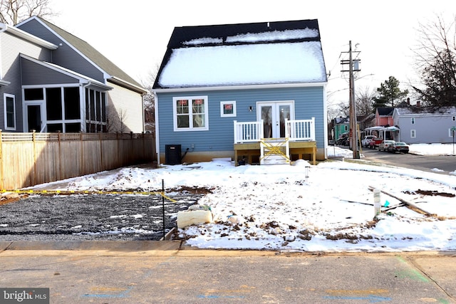 snow covered back of property with cooling unit and french doors