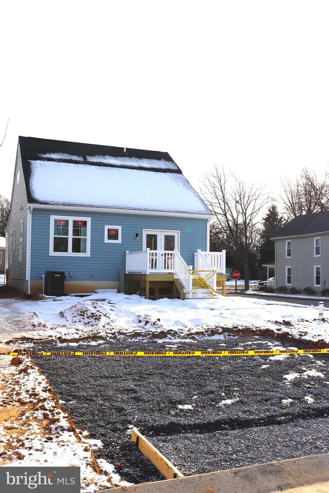 snow covered property with french doors, a deck, and central air condition unit