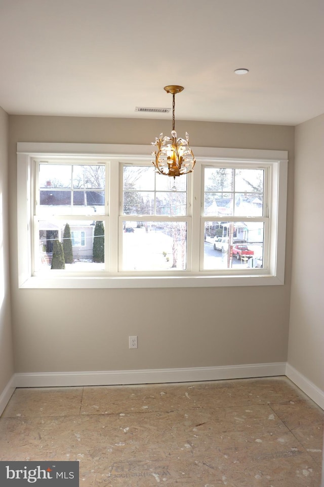 spare room with a notable chandelier and a wealth of natural light