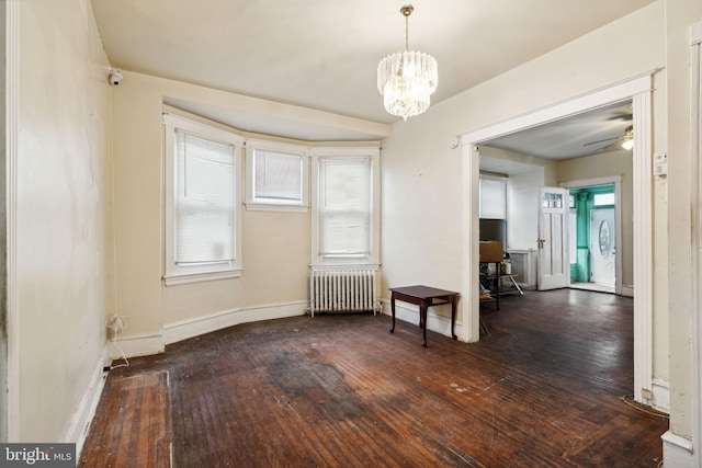 spare room with ceiling fan with notable chandelier, dark hardwood / wood-style floors, and radiator heating unit