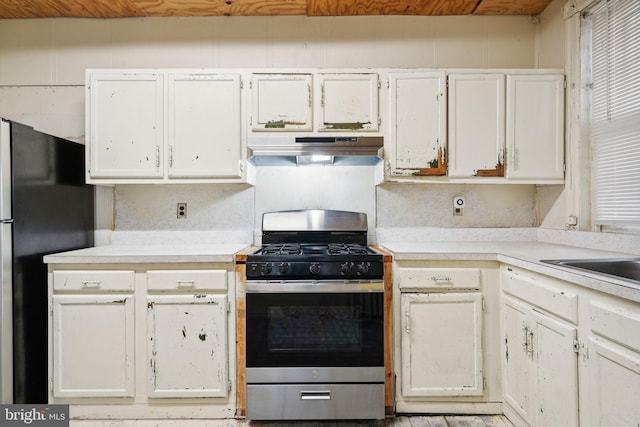 kitchen featuring fridge, white cabinetry, and stainless steel gas range