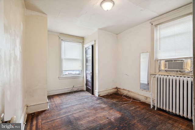 spare room featuring cooling unit, radiator heating unit, and dark hardwood / wood-style flooring