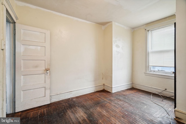 empty room with a wealth of natural light and dark hardwood / wood-style flooring