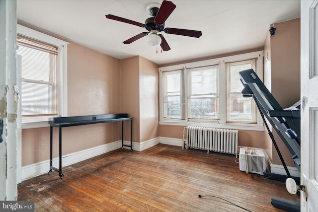 interior space with hardwood / wood-style flooring, a wall mounted air conditioner, radiator heating unit, and a healthy amount of sunlight