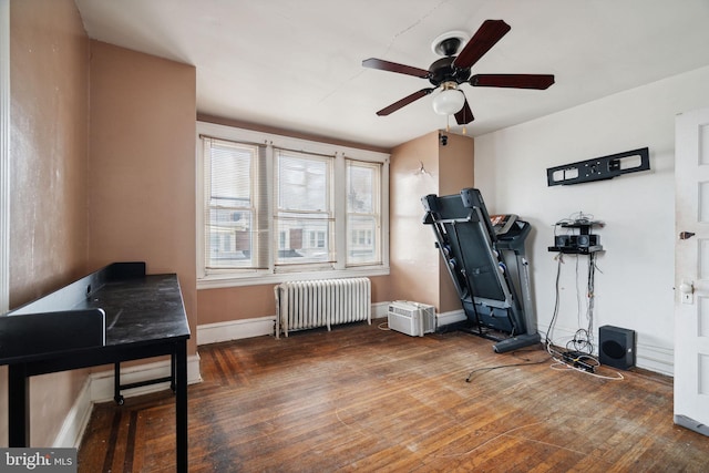 exercise room with ceiling fan, radiator heating unit, and dark wood-type flooring