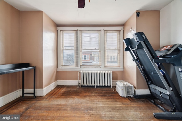 exercise area with radiator heating unit, dark wood-type flooring, and ceiling fan