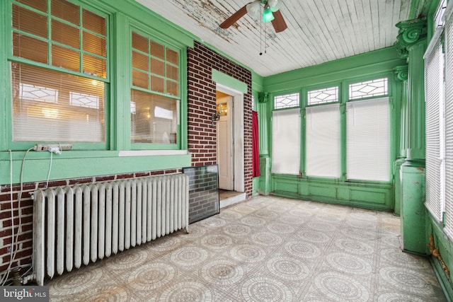 unfurnished sunroom featuring ceiling fan and radiator heating unit