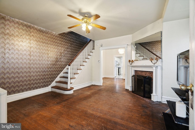 unfurnished living room featuring ceiling fan, dark wood-type flooring, and a fireplace