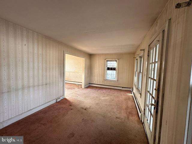 spare room featuring carpet floors and a baseboard heating unit