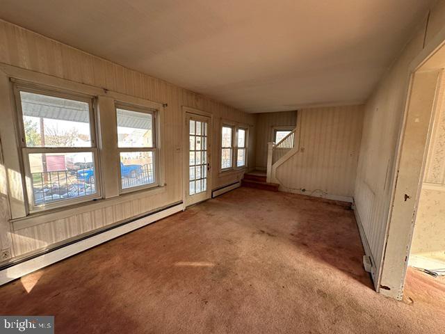 interior space featuring light colored carpet, a healthy amount of sunlight, and a baseboard heating unit