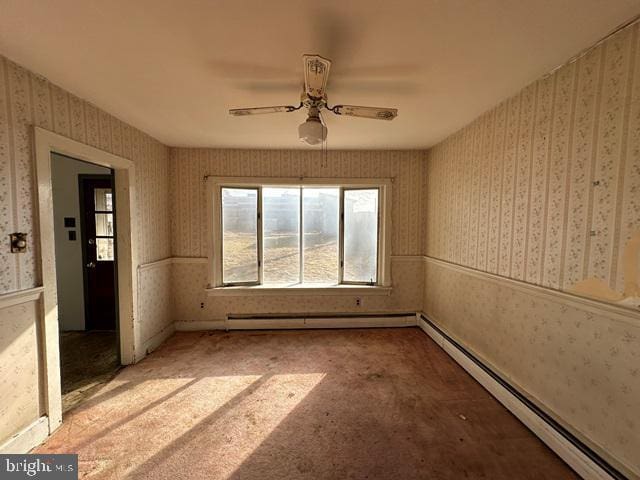 carpeted empty room with ceiling fan and a baseboard heating unit