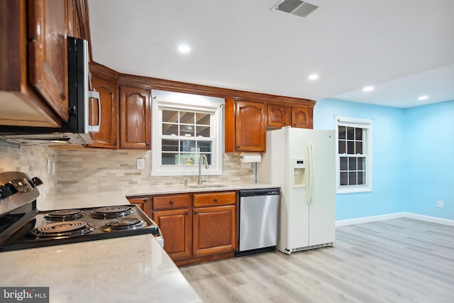 kitchen with decorative backsplash, sink, appliances with stainless steel finishes, and light hardwood / wood-style flooring