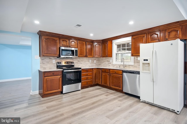 kitchen featuring sink, stainless steel appliances, tasteful backsplash, and light hardwood / wood-style flooring