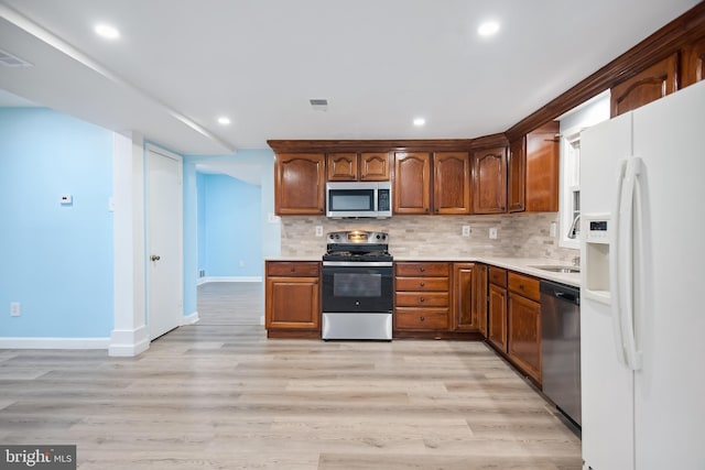 kitchen featuring tasteful backsplash, light wood-type flooring, and appliances with stainless steel finishes