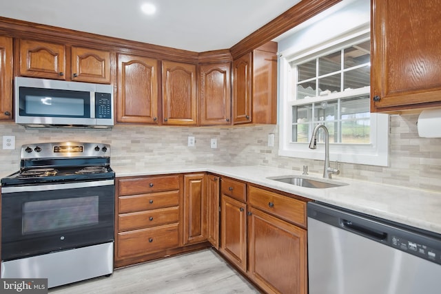 kitchen featuring tasteful backsplash, sink, stainless steel appliances, and light hardwood / wood-style floors