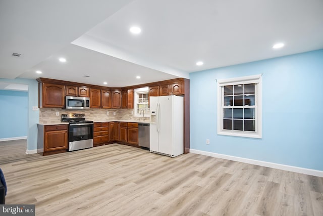 kitchen featuring tasteful backsplash, sink, stainless steel appliances, and light hardwood / wood-style floors