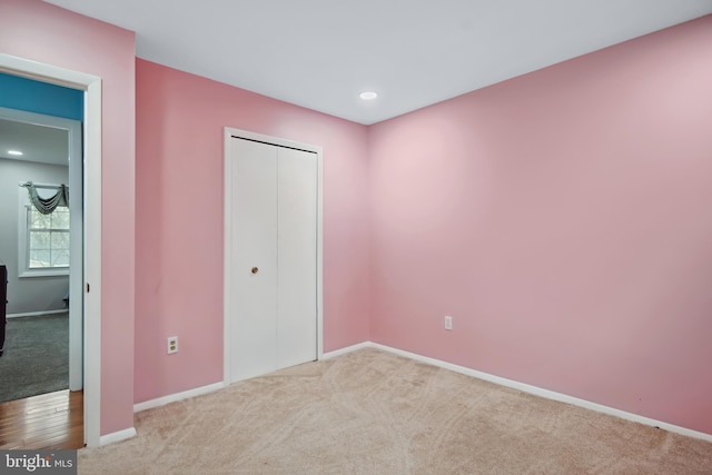 unfurnished bedroom with light carpet and a closet