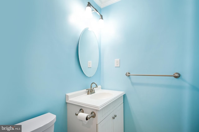 bathroom featuring toilet, vanity, and ornamental molding