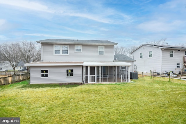 rear view of house with a sunroom, a lawn, and central AC