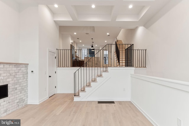 staircase featuring a fireplace, hardwood / wood-style flooring, beamed ceiling, and coffered ceiling