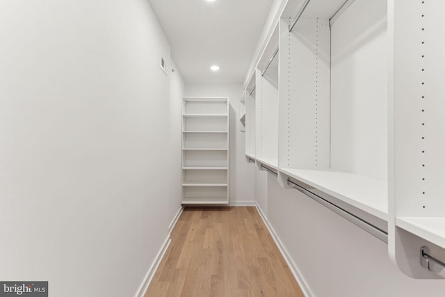 walk in closet with light hardwood / wood-style flooring