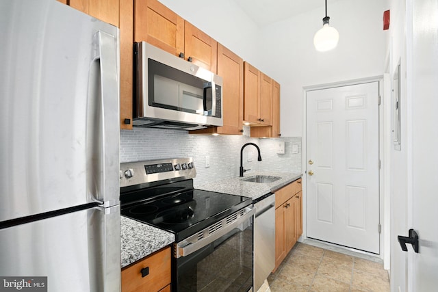 kitchen featuring appliances with stainless steel finishes, backsplash, light stone counters, sink, and hanging light fixtures