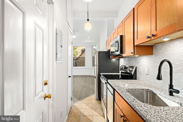 kitchen featuring light stone countertops, stainless steel appliances, hanging light fixtures, and sink