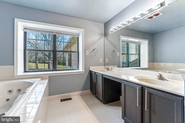 bathroom with tile patterned floors, vanity, and tiled bath