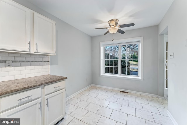 kitchen with dark stone counters, ceiling fan, light tile patterned floors, tasteful backsplash, and white cabinetry