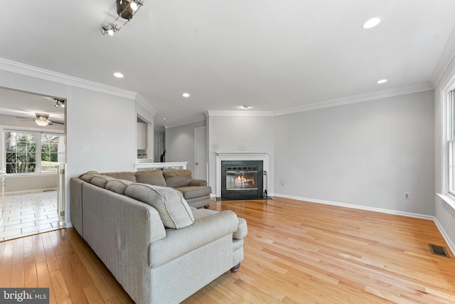 living room featuring light wood-type flooring, ceiling fan, and ornamental molding