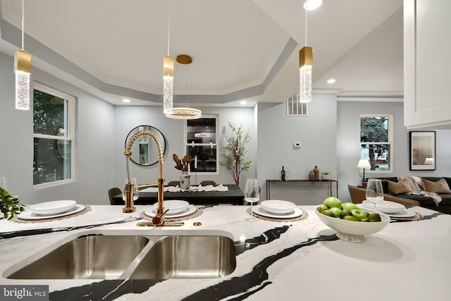 kitchen with white cabinetry, light stone counters, hanging light fixtures, and crown molding