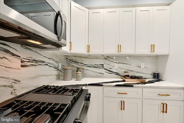 kitchen with decorative backsplash, white cabinets, and stainless steel appliances