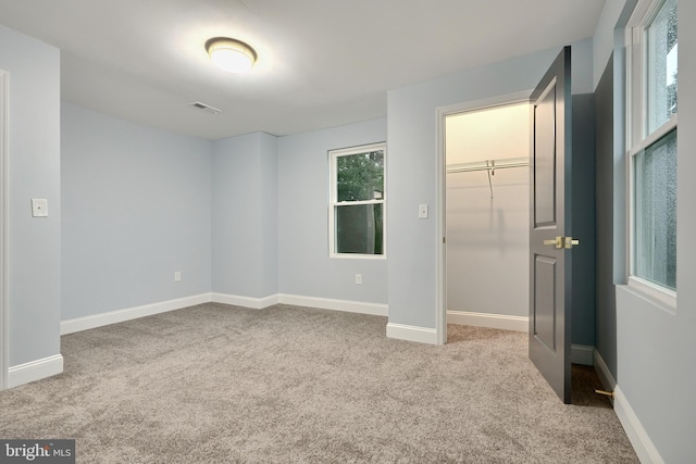 interior space with light colored carpet, a walk in closet, and a closet