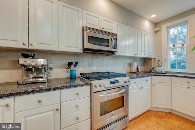 kitchen with tasteful backsplash, sink, white cabinets, and appliances with stainless steel finishes