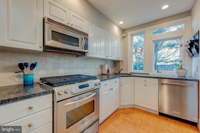 kitchen featuring tasteful backsplash, white cabinetry, sink, dark stone countertops, and stainless steel appliances