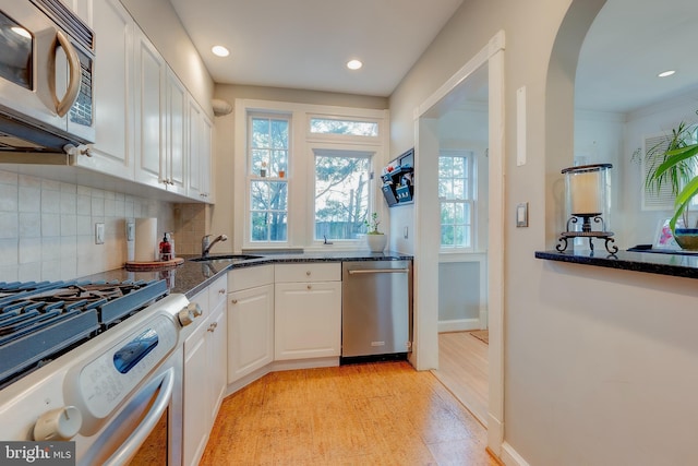 kitchen featuring white cabinetry, sink, dark stone countertops, backsplash, and stainless steel appliances