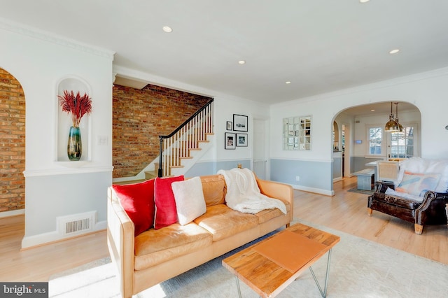 living room featuring ornamental molding, light hardwood / wood-style floors, and brick wall