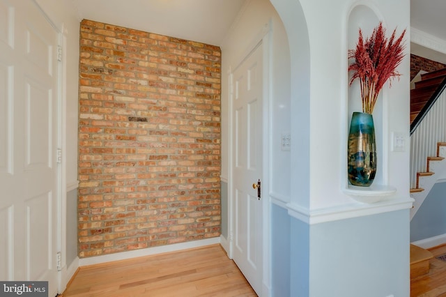 hall featuring brick wall and light hardwood / wood-style flooring