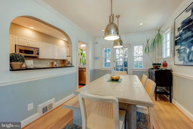 dining space with light hardwood / wood-style flooring and ornamental molding