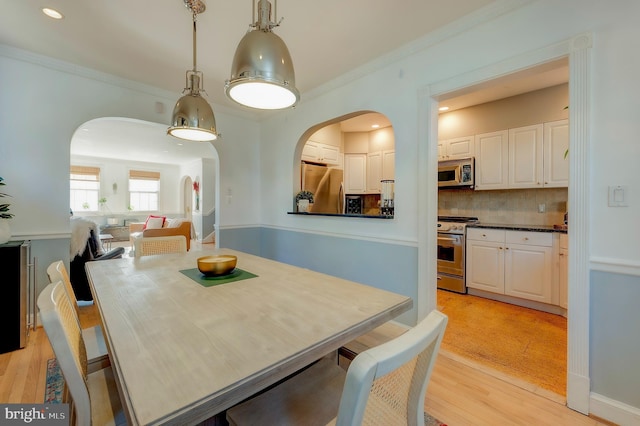 dining room with crown molding and light wood-type flooring