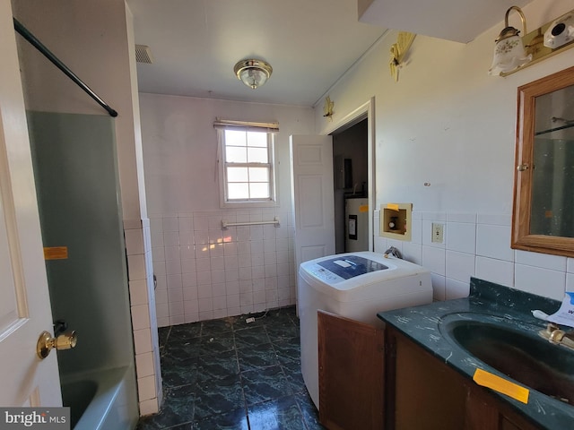 bathroom with washer / dryer, vanity, tile walls, and water heater