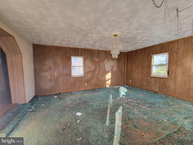 unfurnished room with wood walls and a notable chandelier