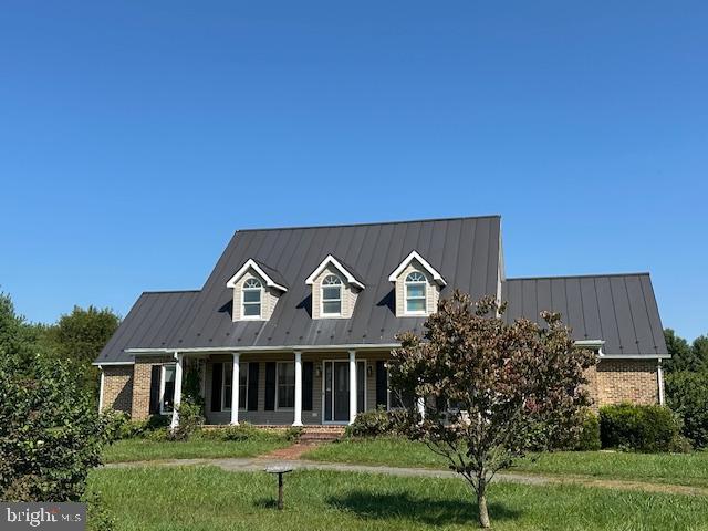 cape cod house featuring a front yard