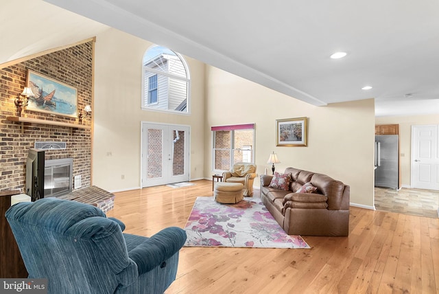 living room with a high ceiling, light hardwood / wood-style floors, and french doors