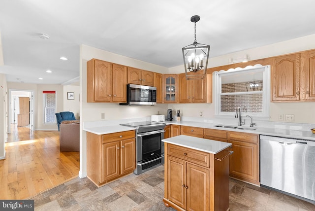 kitchen with sink, appliances with stainless steel finishes, hanging light fixtures, a notable chandelier, and a kitchen island