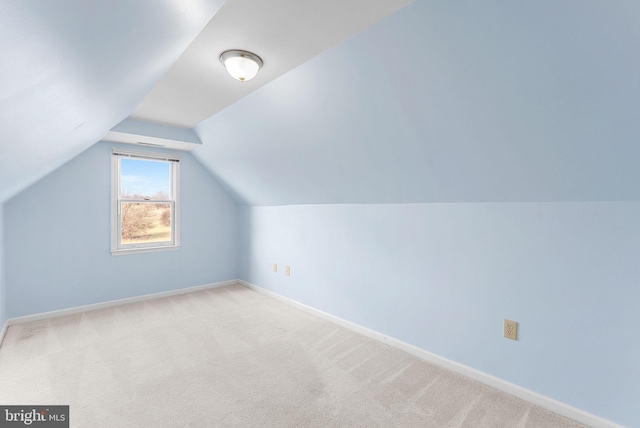 additional living space featuring light colored carpet and vaulted ceiling