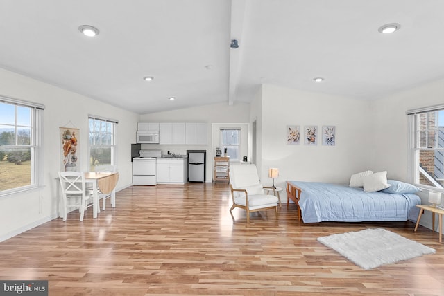 bedroom featuring multiple windows, vaulted ceiling with beams, and light wood-type flooring