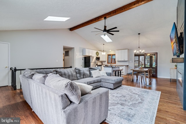 living area with high vaulted ceiling, a fireplace, a skylight, wood finished floors, and beamed ceiling